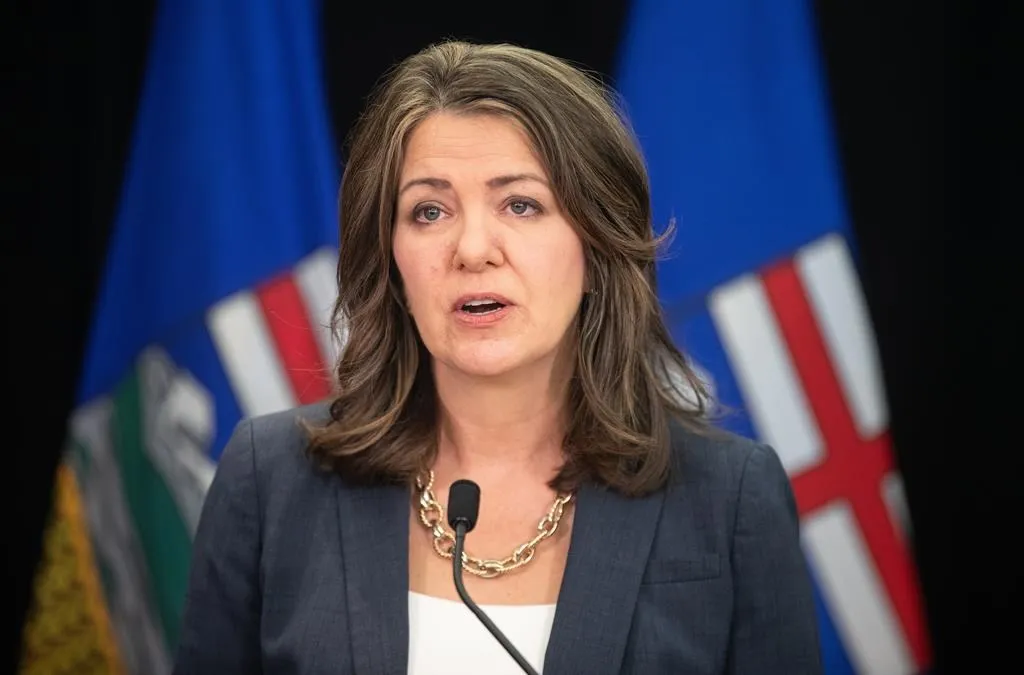 Alberta Premier Danielle Smith speaking at an event, with flags in the background symbolizing international diplomacy.