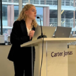 Jessie Shaw presenting sustainability insights at a real estate Capstone event with panelists.