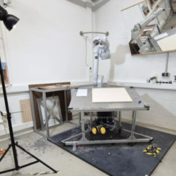 Robotic arm painting a flower on canvas in a university art and tech lab.