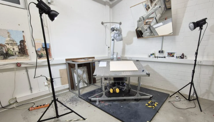 Robotic arm painting a flower on canvas in a university art and tech lab.