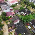 Drone view of flooded towns in Sumatra, Indonesia, with submerged houses, collapsed bridges and rescue boats searching for missing residents after cyclone-driven torrential rain.