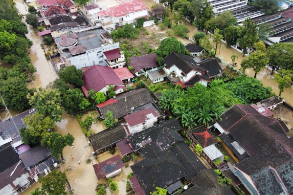 Drone view of flooded towns in Sumatra, Indonesia, with submerged houses, collapsed bridges and rescue boats searching for missing residents after cyclone-driven torrential rain.