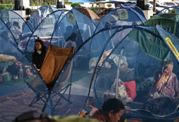 A person carrying a child at a refugee camp after evacuation in Srei Snam, Cambodia, during Thailand-Cambodia clashes.