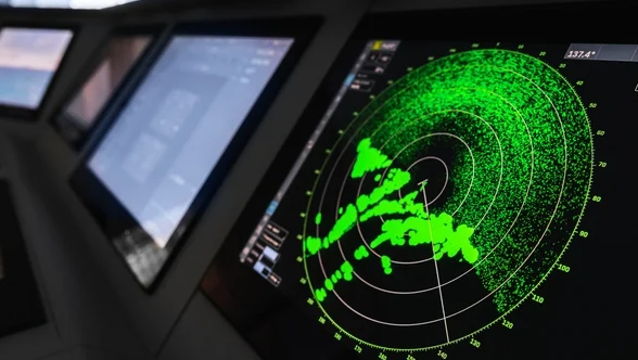 Irish Defence Forces personnel inspecting a modern military radar installation near the coast.