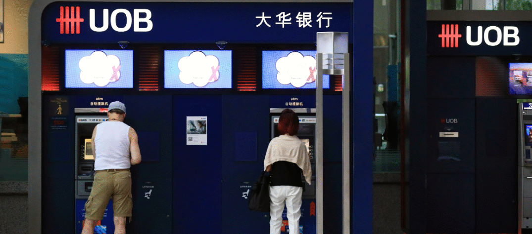 UOB bank headquarters with Hong Kong skyline in the background, highlighting property loan exposure challenges.