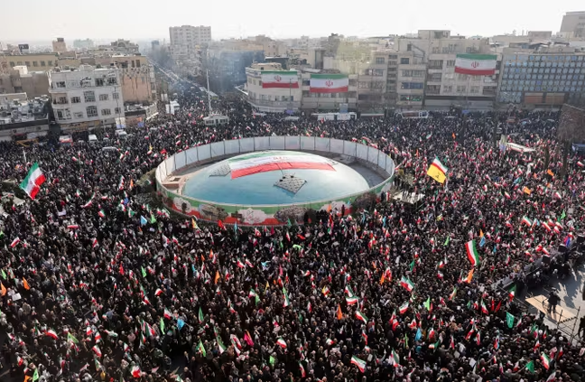 Protesters gather on a street in Iran during the 2025–2026 nationwide demonstrations, holding anti-government signs amid a heavy security presence.